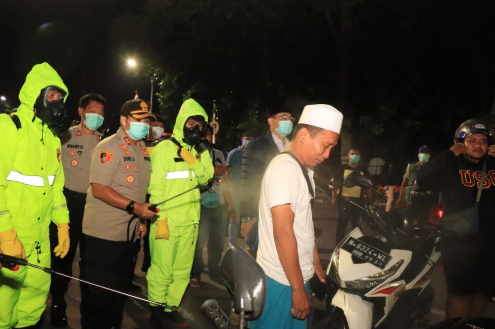 Warga Kota Pasuruan yang berkerumun disemprot disinfektan sebelum diminta bubar