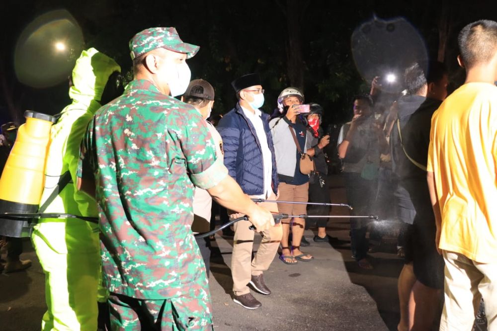 Warga Kota Pasuruan yang berkerumun disemprot disinfektan sebelum diminta bubar