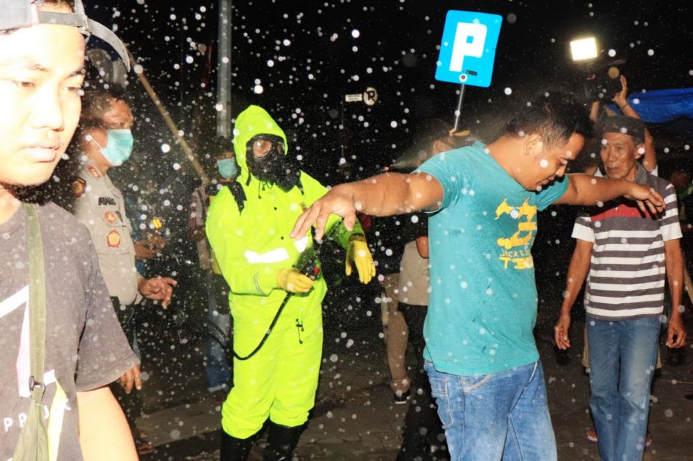 Warga Kota Pasuruan yang berkerumun disemprot disinfektan sebelum diminta bubar
