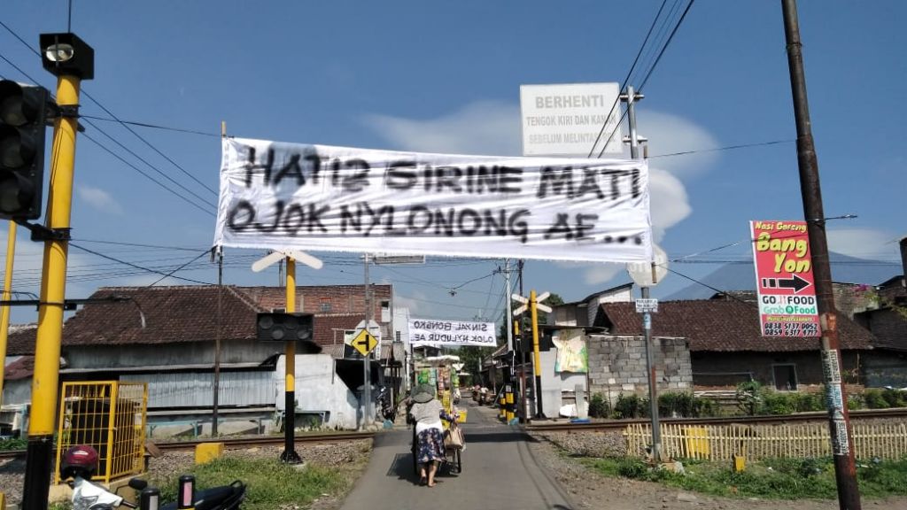 Spanduk 'pedes' yang dipasang warga di atas perlintasan kereta api