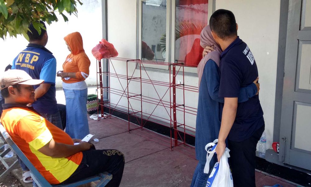 Salah satu narapidana memeluk istrinya setelah mendengar pelarangan kunjungan ke Lapas Pasuruan dalam beberapa hari ke depan