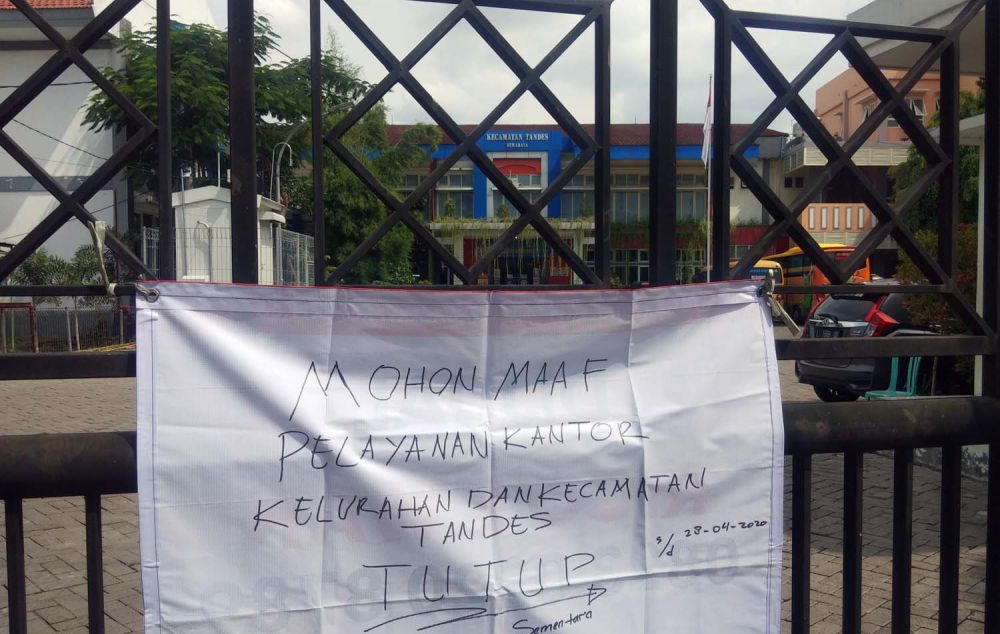 Tulisan informasi yang ditempelkan di pagar pintu masuk Kantor Kecamatan dan Kelurahan Tandes, Surabaya