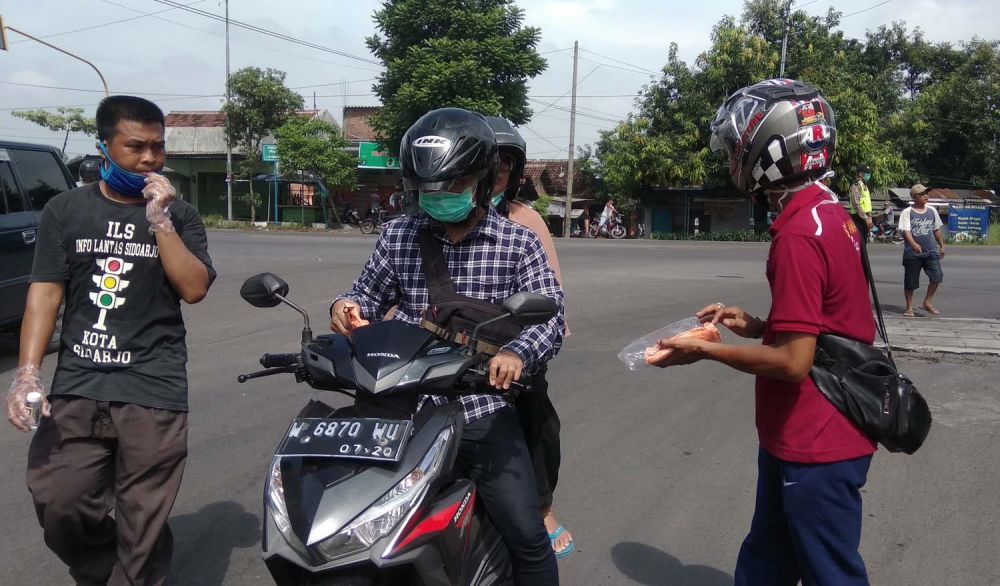 Netizen membagikan masker dan hand sanitizer kepada pengguna jalan di Simpang Empat Prambon, Sidoarjo