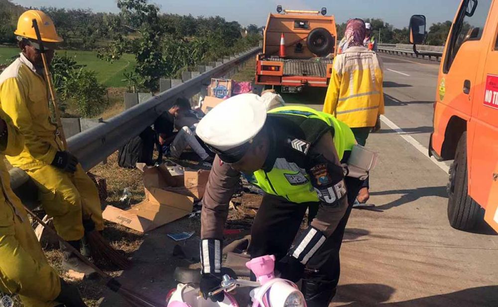 Petugas PJR Polda Jatim membantu mengumpulkan barang-barang penumpang Isuzu Elf yang terguling di Tol Jombang 