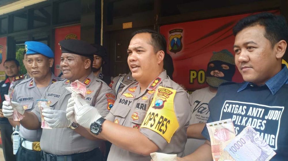 Kapolres Jombang AKBP Boby Palu'din Tambunan menujukkan uang yang disita dari tiga pejudi pilkades serentak