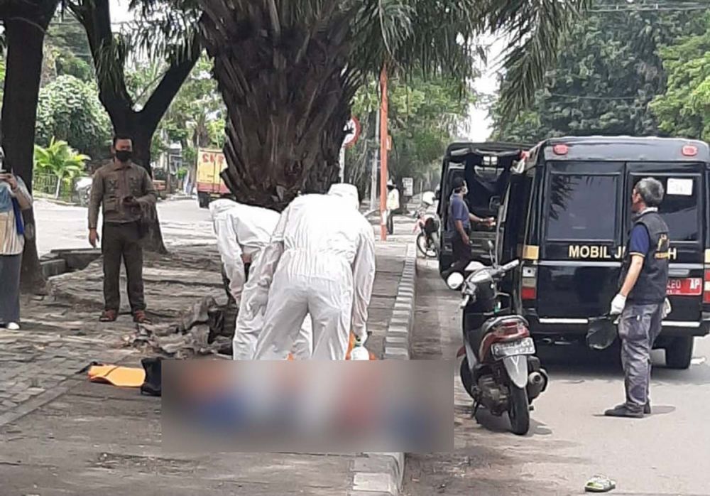 Petugas berpakaian APD mengevakuasi jenazah pengendara motor di Jalan Raya Margomulyo, Surabaya