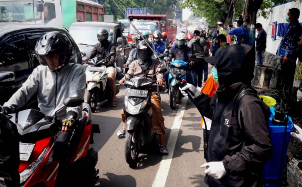 Para pengendara dari Surabaya yang akan masuk Gresik disemprot disinfektan