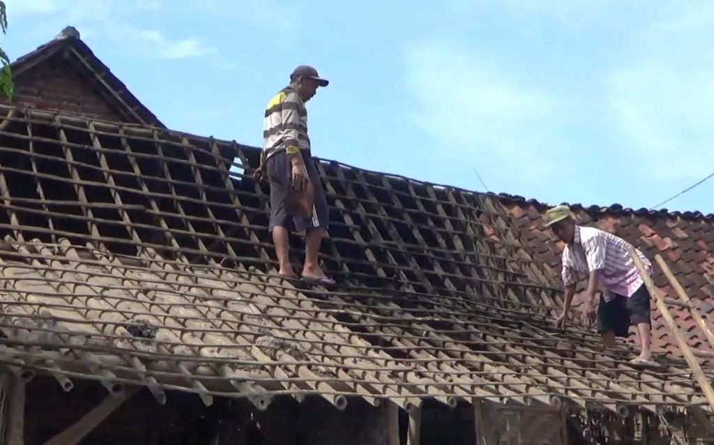 Warga di Pasuruan memperbaiki rumahnya yang rusak akibat hujan angin