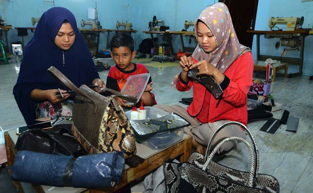 Para pekerja sedang membuat tas berbahan kulit ular di Banyuwangi