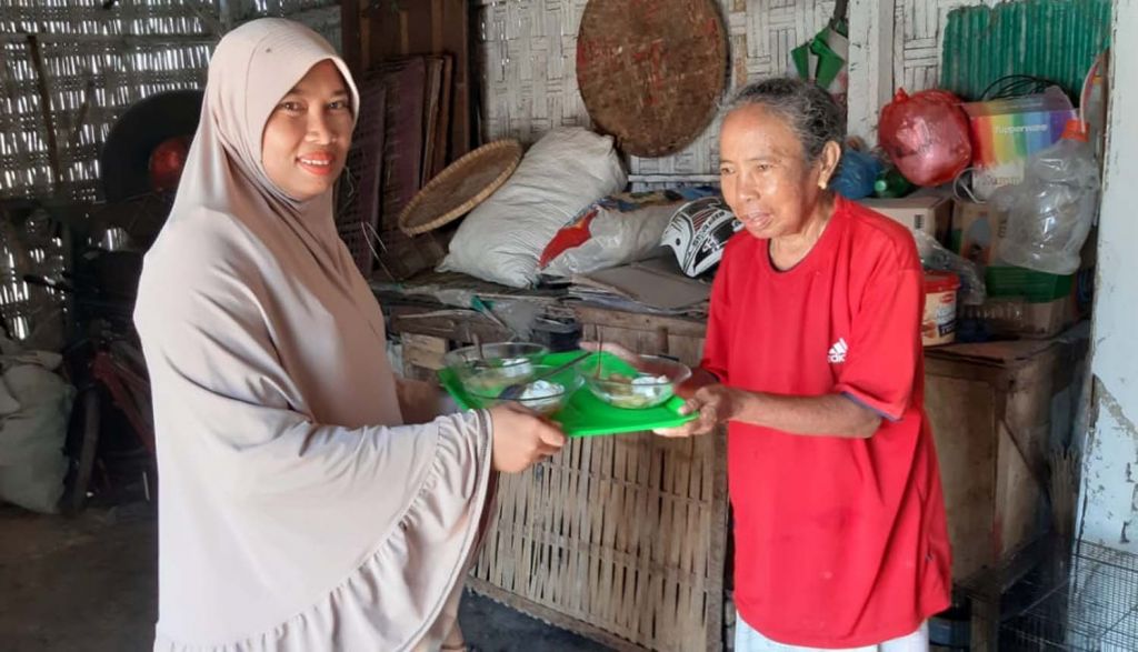 Seorang warga membagikan jenang ke tetangga dalam tradisi sedekah jenang sapar di Probolinggo