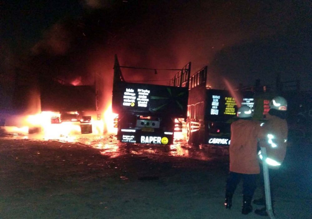 Petugas Dinas Pemadam Kebakaran Kota Surabaya berusaha memadamkan api yang membakar truk