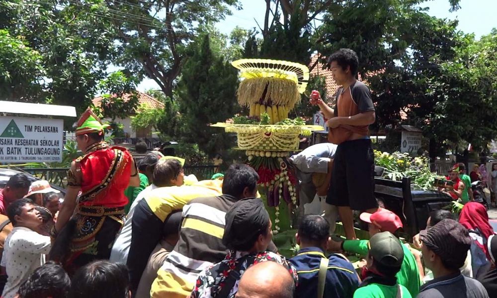 Warga berebut buahan-buahan dan lauk pauk pada tumpeng dalam Upacara Adat Bersih Nagari di Tulungagung