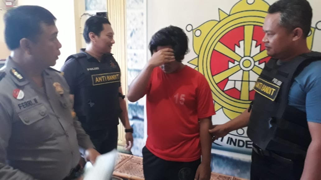 Arifin (menutup muka) diamankan di Mapolsek Pakal Surabaya.